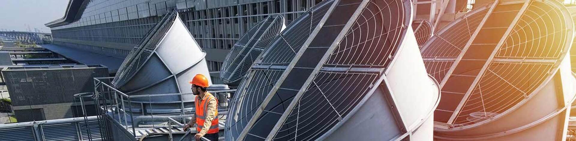 Technician inspecting large rooftop cooling tower fans for air quality systems in Greensboro, NC