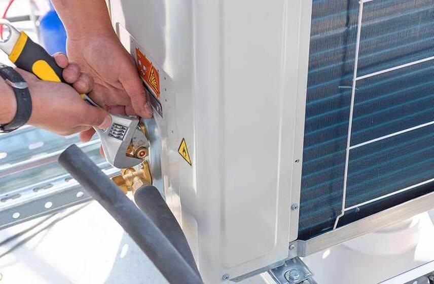 Commercial HVAC technician servicing outdoor air conditioning equipment for a business in Wilmington, NC