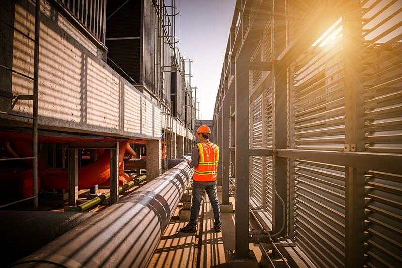 Greensboro NC commercial HVAC technician inspecting large-scale cooling tower and piping system