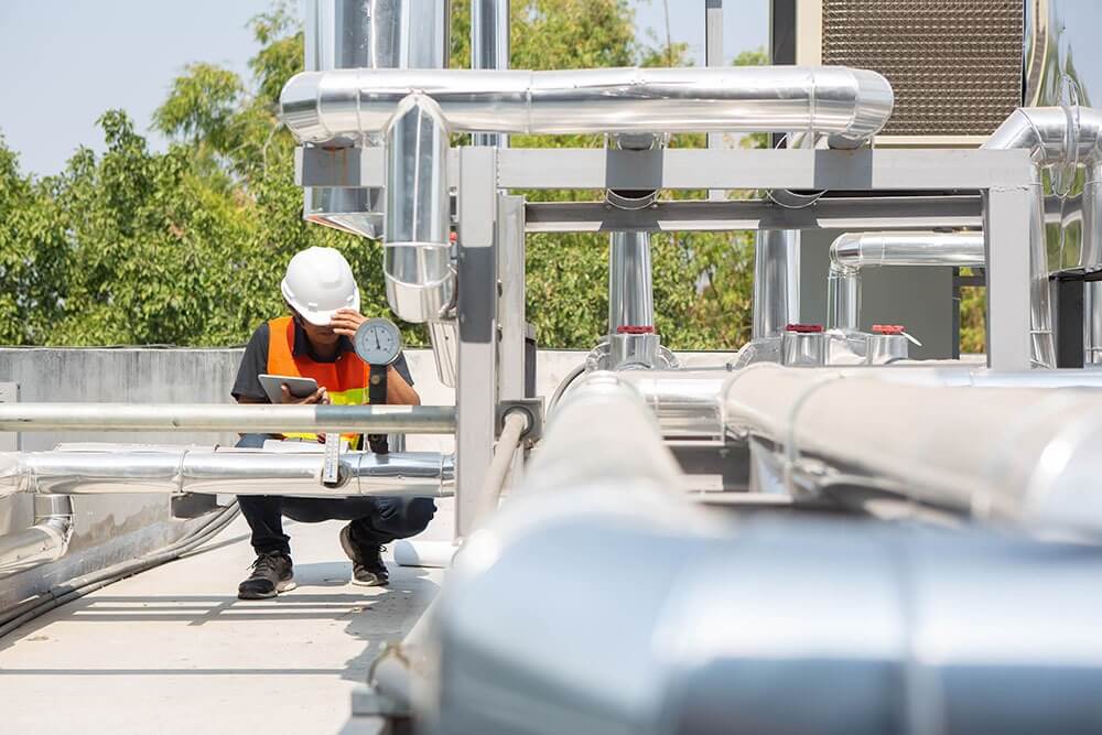 Technician reviewing chiller piping pressure readings for HVAC engineering and design services