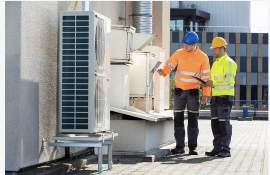 Two technicians reviewing industrial air conditioning services for a Wilmington, NC facility