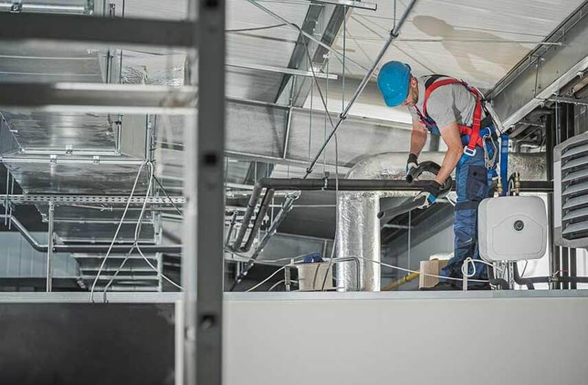 Technician performing HVAC maintenance on commercial ductwork system in Reidsville, NC
