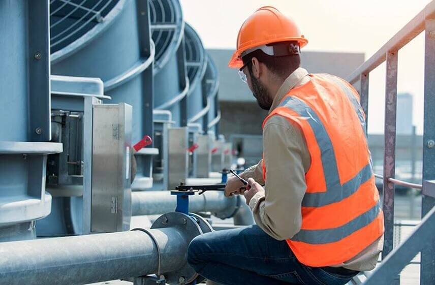 Commercial HVAC company technician inspecting and adjusting rooftop pipe valve system